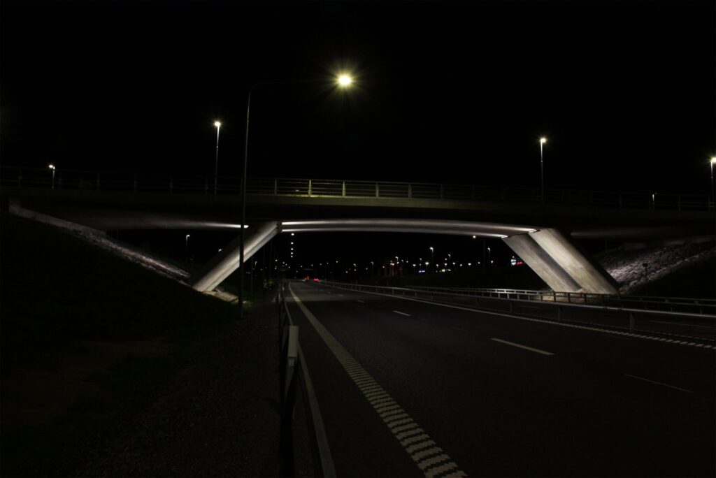 Tom motorväg nattetid under belyst betongbro vid Västra länken.