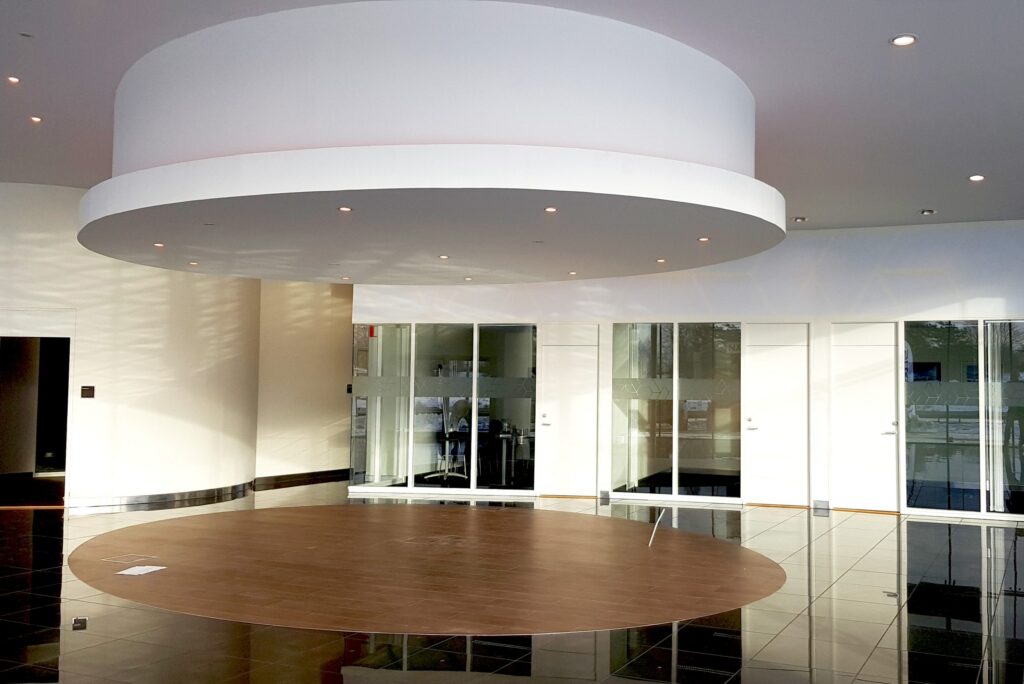 Lexus-lobby med cirkulärt nedsänkt tak, infällda spotlights och rund träinläggning i golvet.