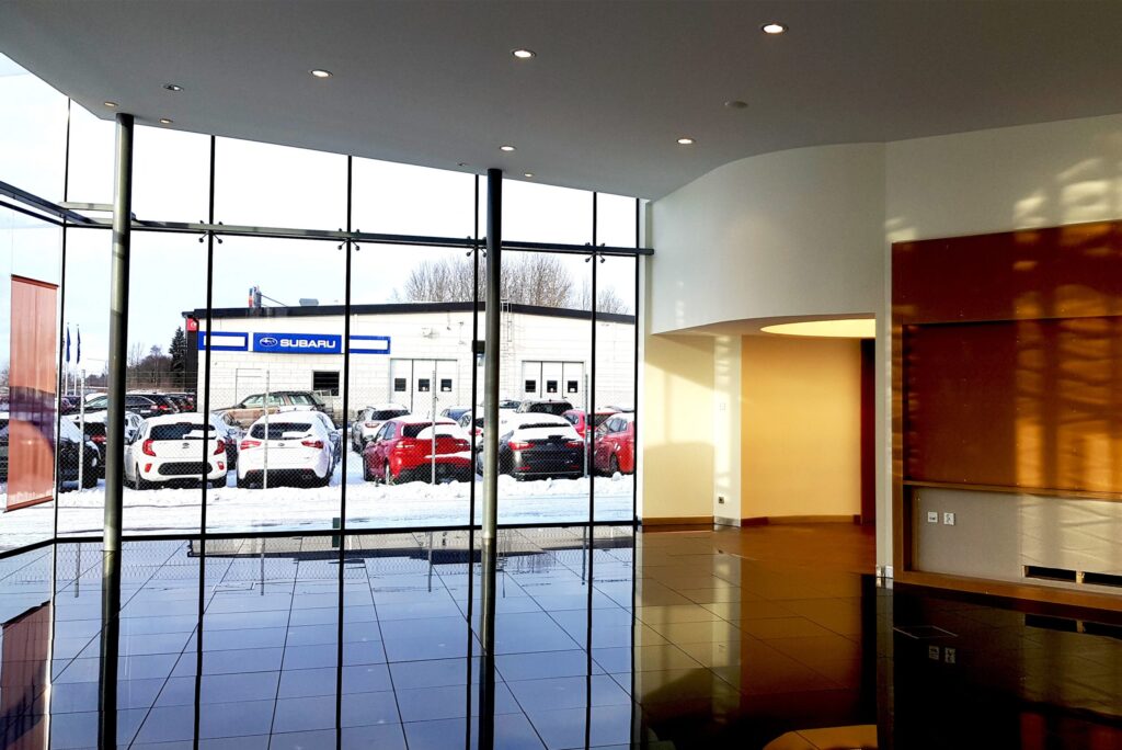 Lexus-showroom med speglande golv, glasfasad och bilar på parkeringen utanför.
