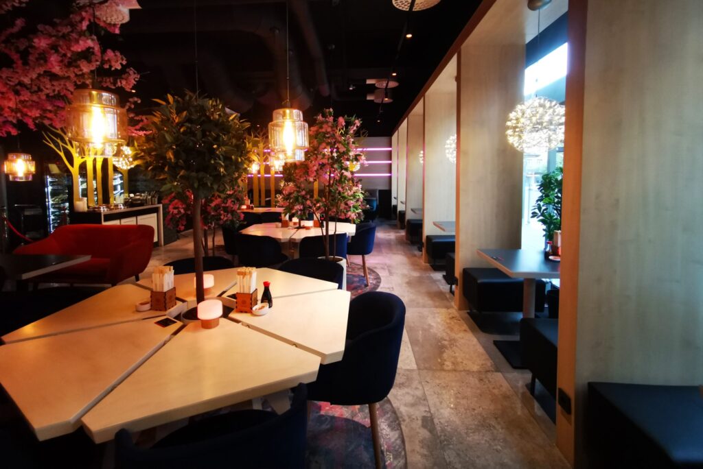 Matsal på Sushi Nara med mörka stolar, körsbärsblom och varma pendellampor över borden.