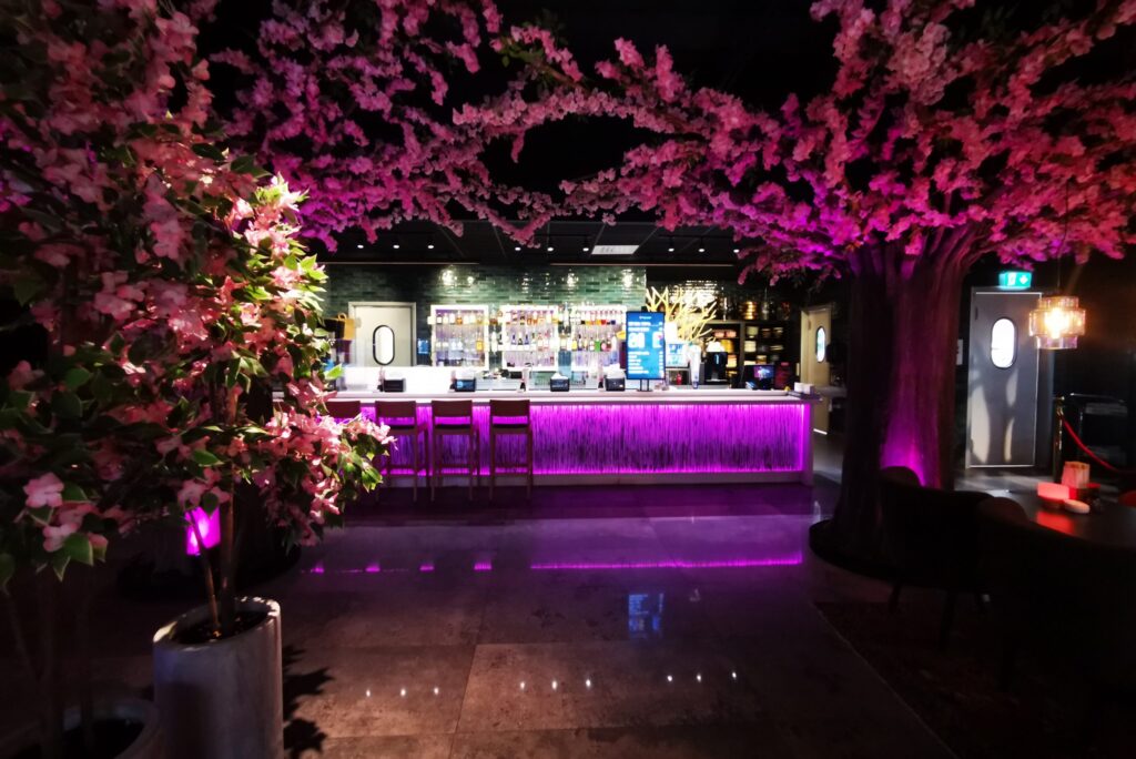 Sushi Nara-baren i magenta ljus med belyst bardisk och körsbärsträd i taket.