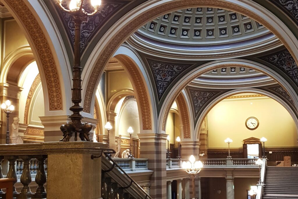 Trapphall i Universitetshuset med dekorerade valv, klotlampor och kassettak i kupolen.