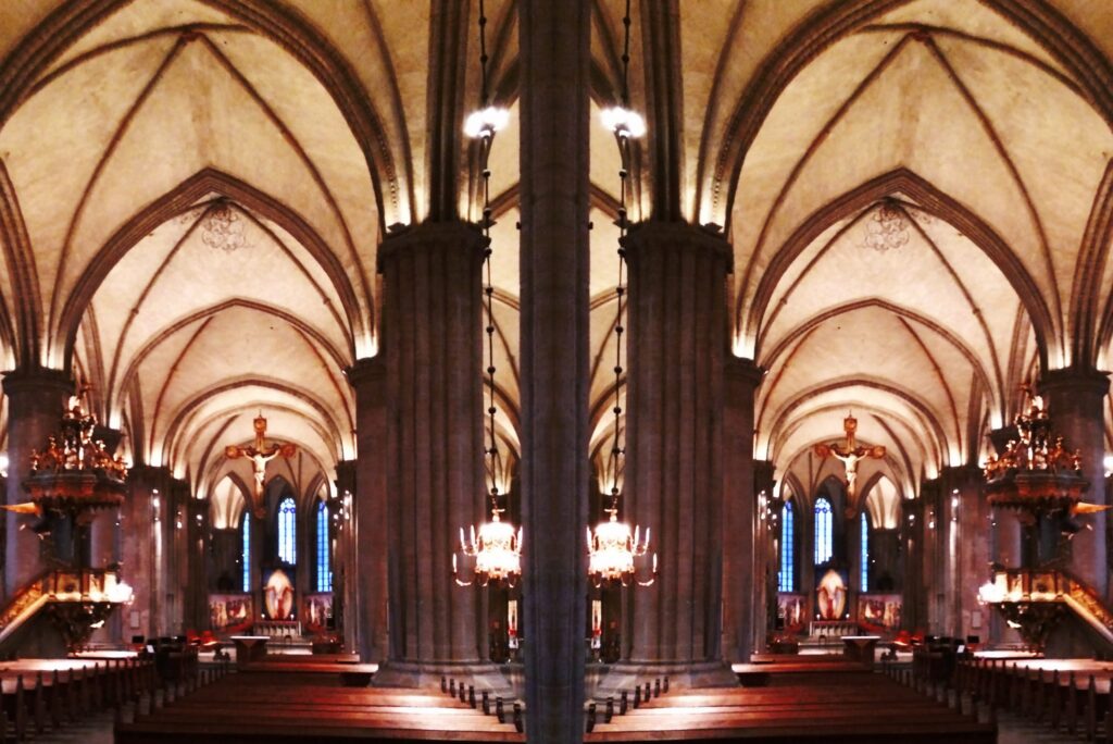 Linköpings domkyrka med ribbvalv, pelare och varmt ljussken mot koret.