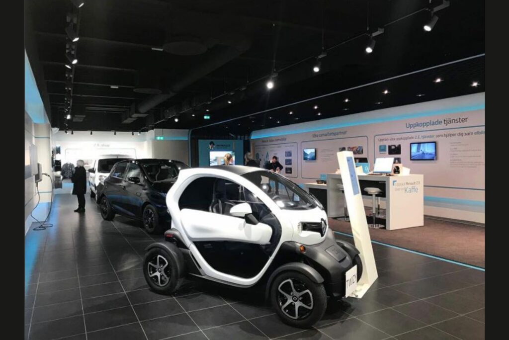 Renault-showroom med skenspotlights i svart tak över en vit Twizy och informationsvägg.