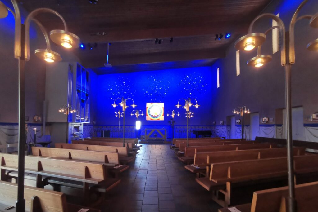 S:t Hans kyrka med blå belyst kor, orgelpipor till vänster och varma golvlampor i mittgången.